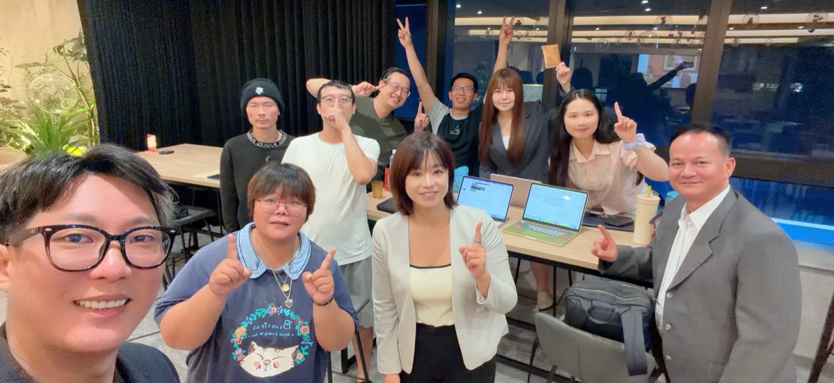 晚上的工作現場合影，桌上放著筆電